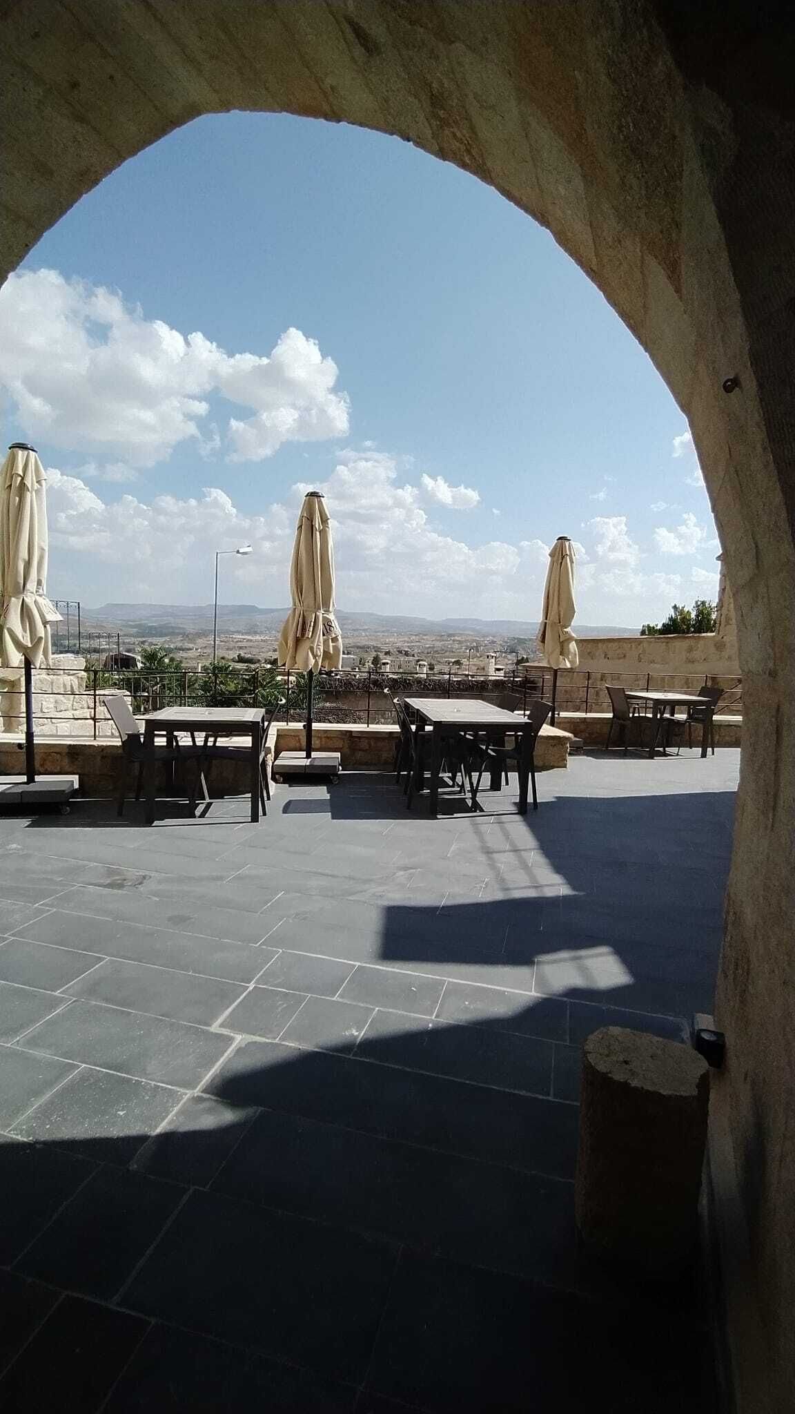 An outdoor seating area with tables and umbrellas, overlooking a scenic landscape.