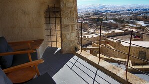 A stone-walled room with a view of a cityscape.