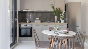 Een moderne keuken met een eethoek, voorzien van een inbouwoven, een koelkast en een eettafel met stoelen.