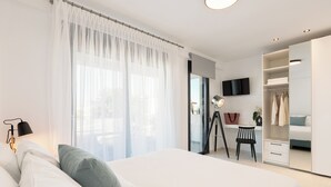 Een moderne slaapkamer met een groot bed, een bureau, een stoel, een kledingkast en een televisie.