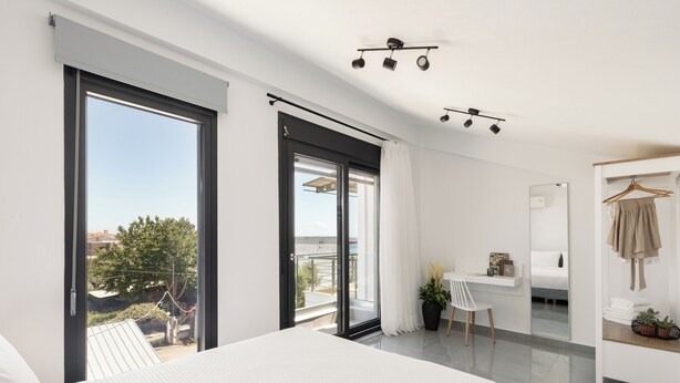 Een moderne slaapkamer met een groot bed, een bureau en een balkon met uitzicht.