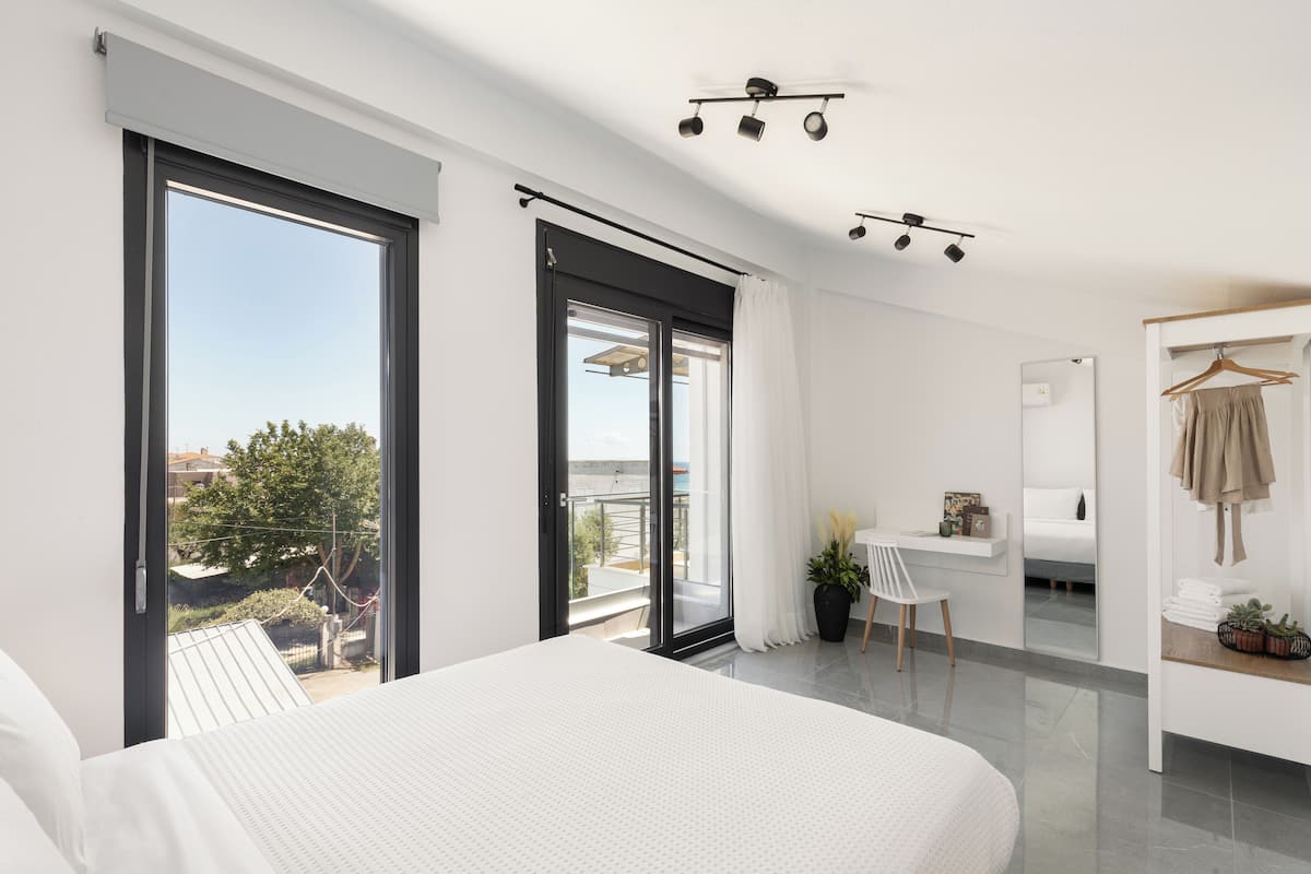 Un dormitorio moderno con una cama grande, un escritorio y un balcón con vistas.