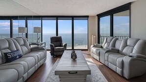 A modern living room with two leather sofas, a coffee table, and a view of the ocean.