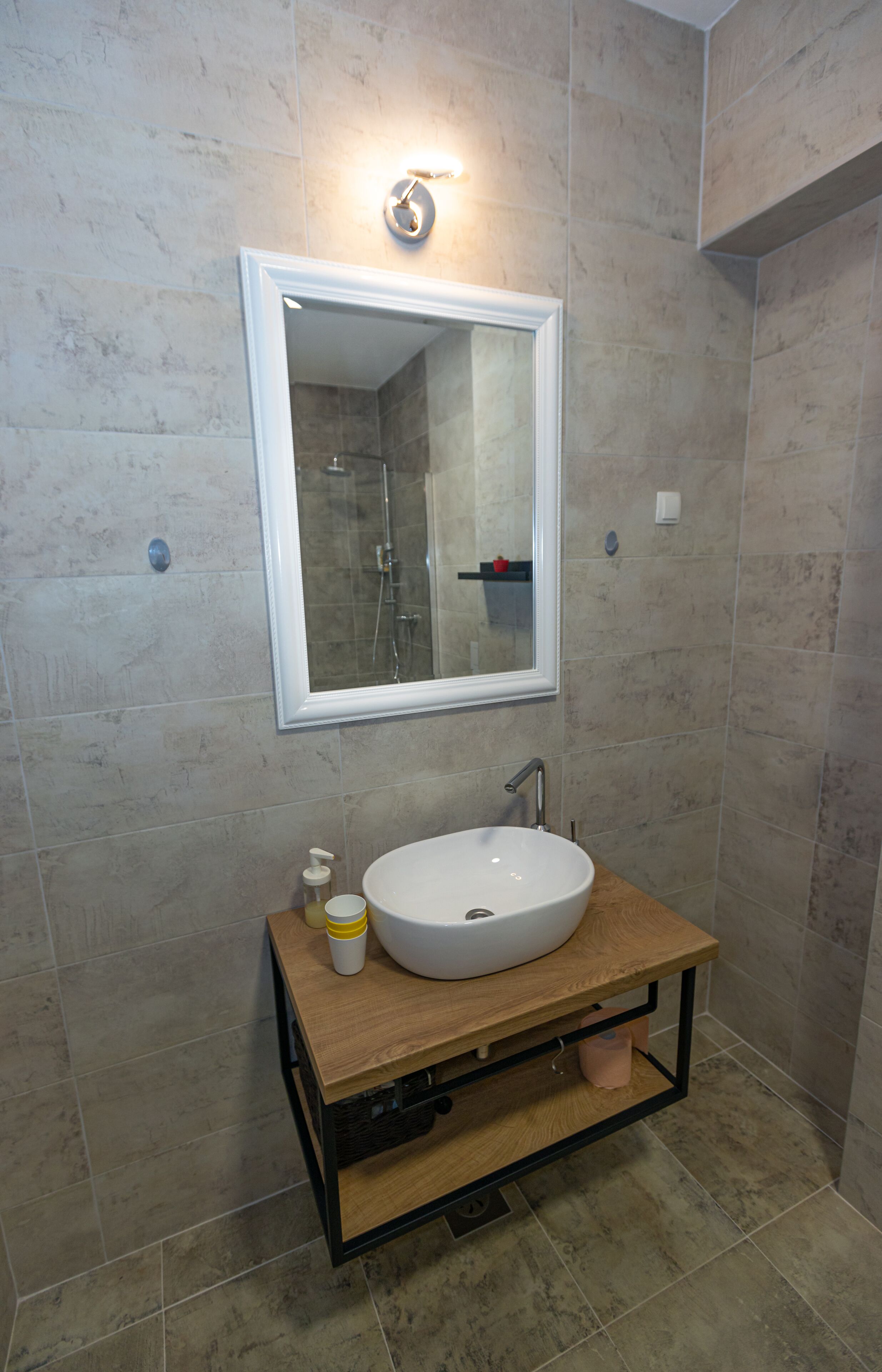 Un baño con un lavabo blanco, un espejo y un mueble de tocador de madera.