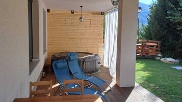 Un área de estar al aire libre cubierta con una terraza de madera, una silla lounge azul y una mesa de madera.