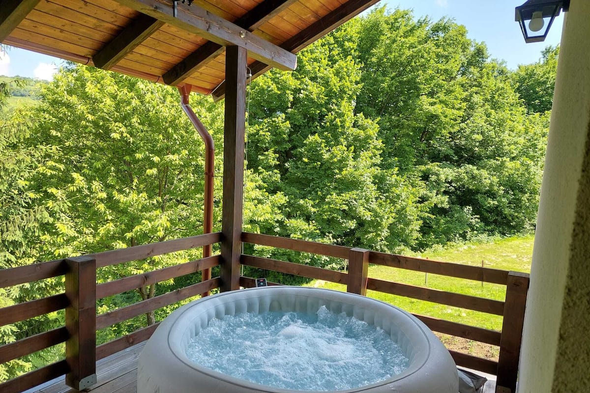 A hot tub on a wooden deck with a view of a forest.