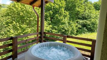 Un jacuzzi en una terraza de madera con vistas a un bosque.