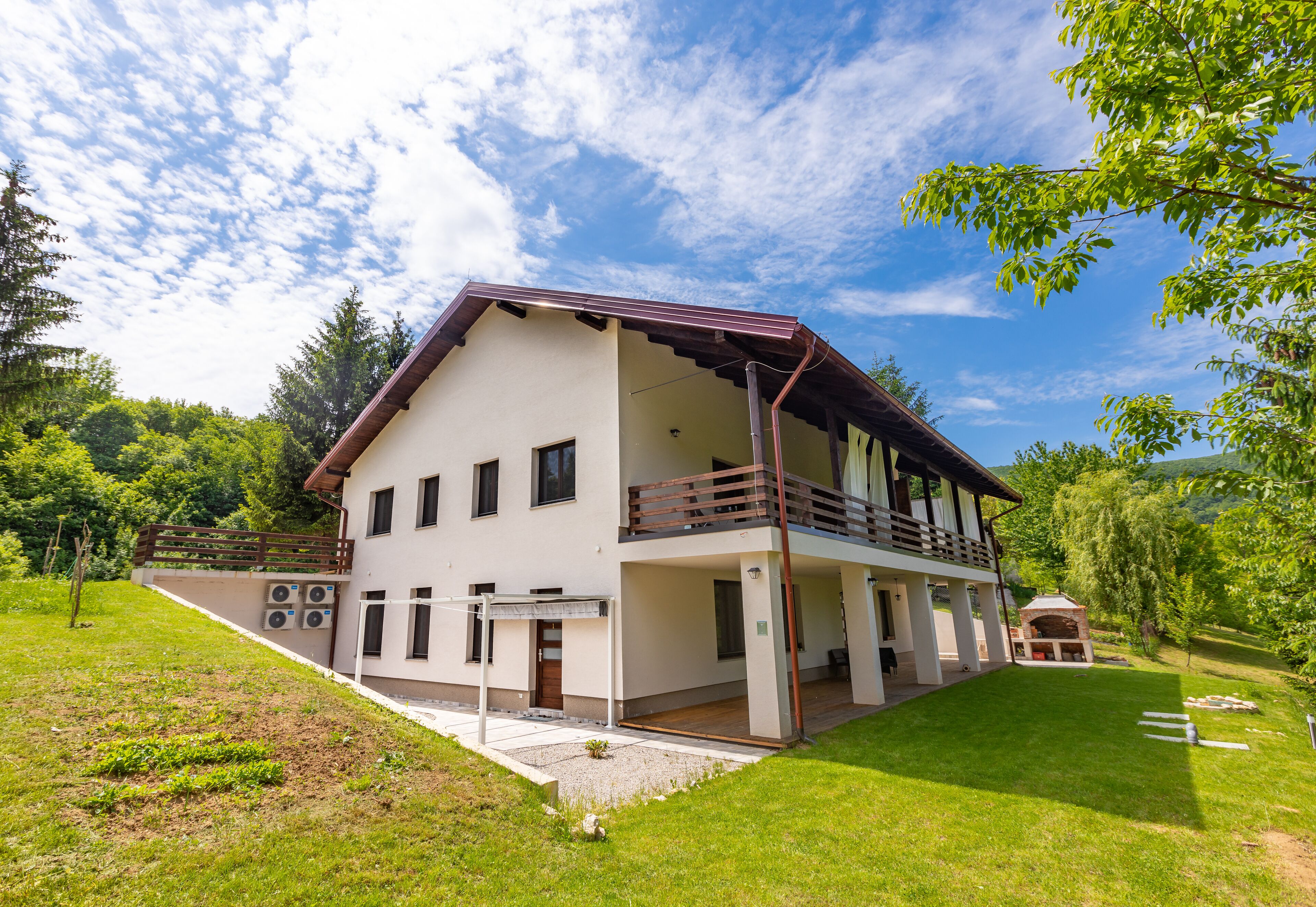 Une maison à deux étages dotée d’un balcon, d’un porche couvert et d’un petit jardin.