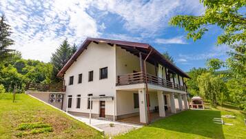 Une maison à deux étages dotée d’un balcon, d’un porche couvert et d’un petit jardin.