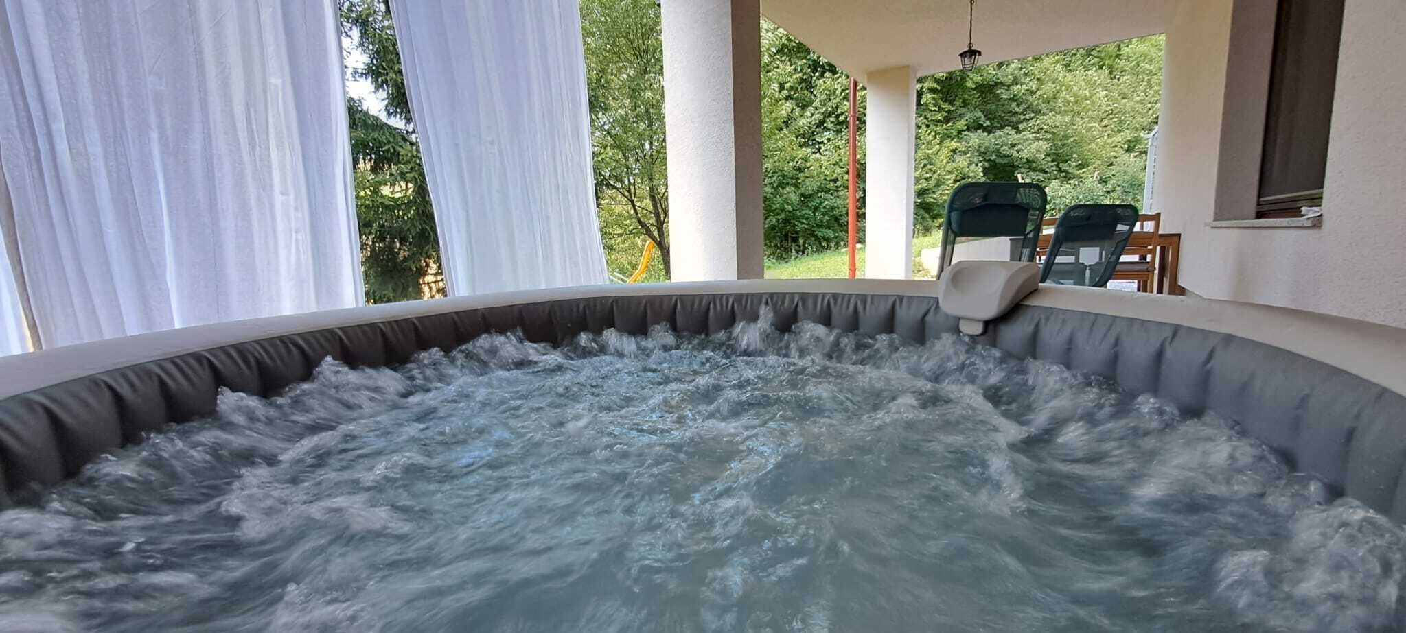 A hot tub with a view of a garden and outdoor seating.