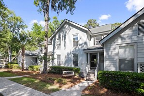 A row of white two-story houses with a front porch and a small front yard.