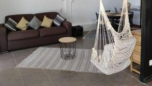 Uma sala de estar moderna com um sofá marrom, tapete estampado e uma cadeira suspensa branca.
