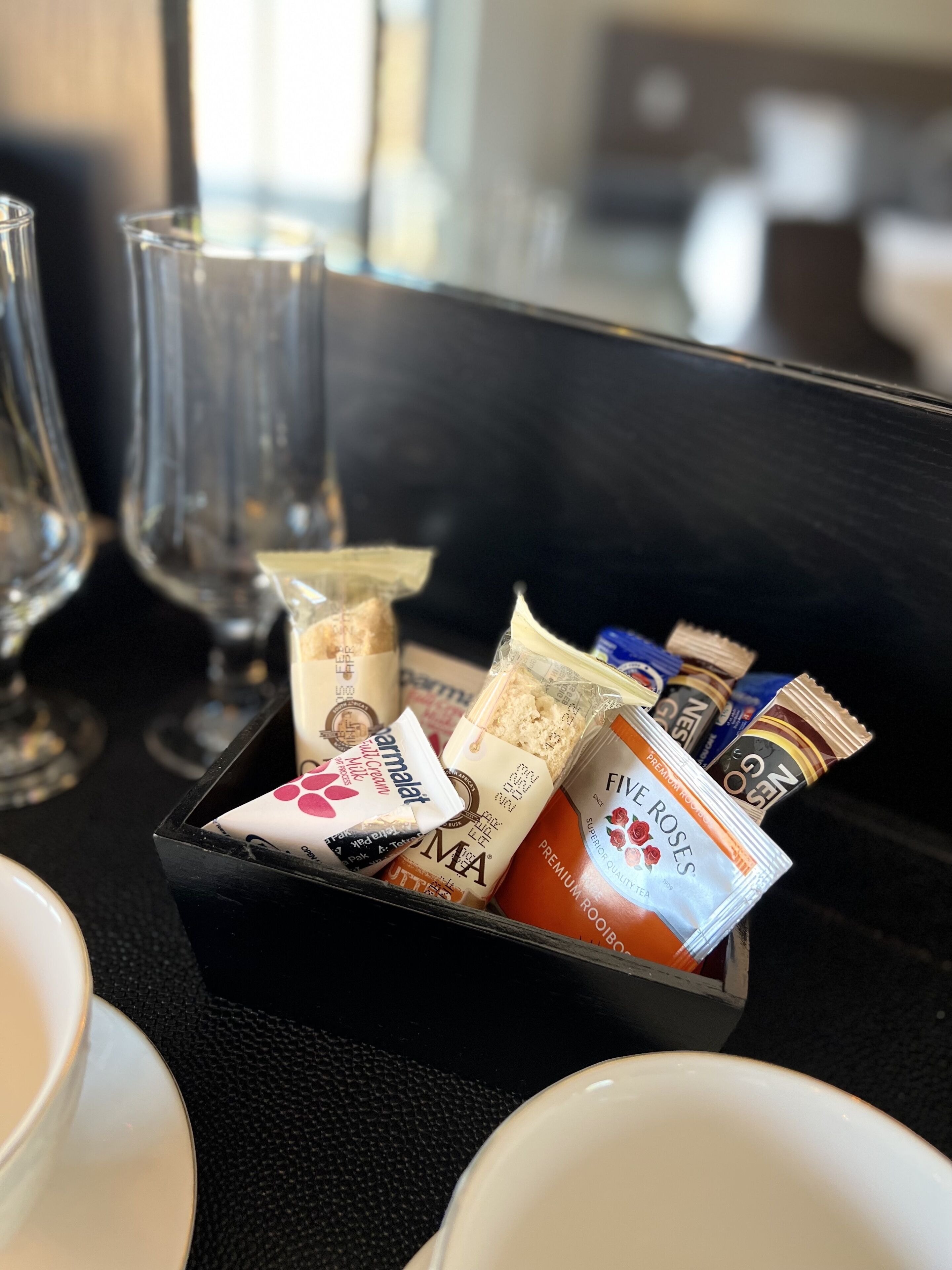 A tray of assorted packaged snacks and a glass of water on a table.