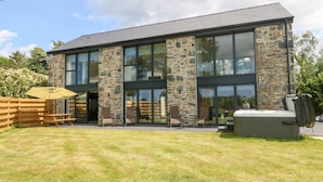 Un bâtiment moderne à l’extérieur en pierre et en verre, doté d’une terrasse et d’une cour verdoyante.