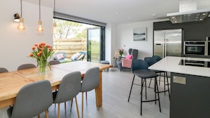Une cuisine moderne avec une table à manger en bois, des chaises grises et un four encastré.