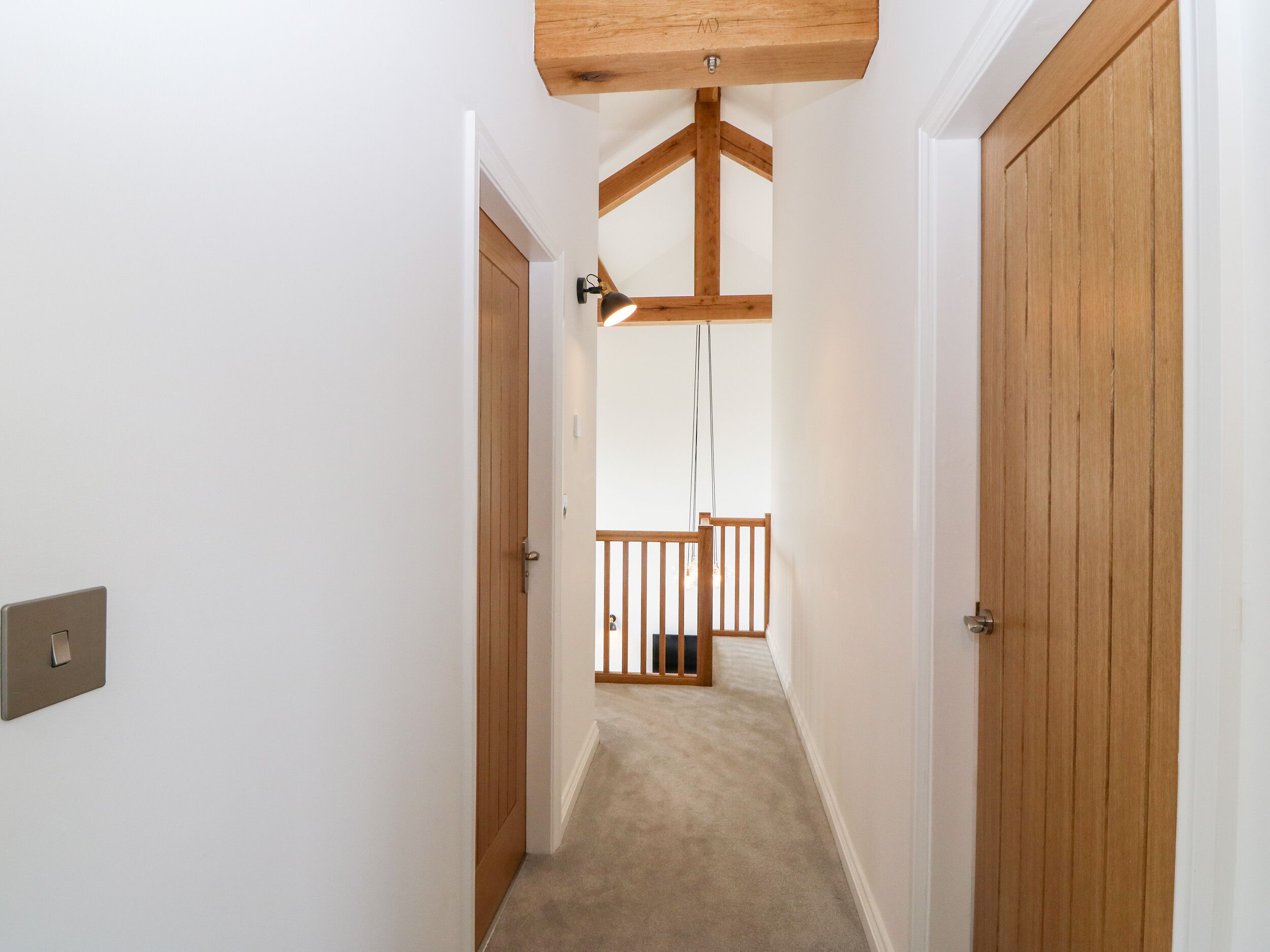 A narrow hallway with wooden doors and a ceiling beam.