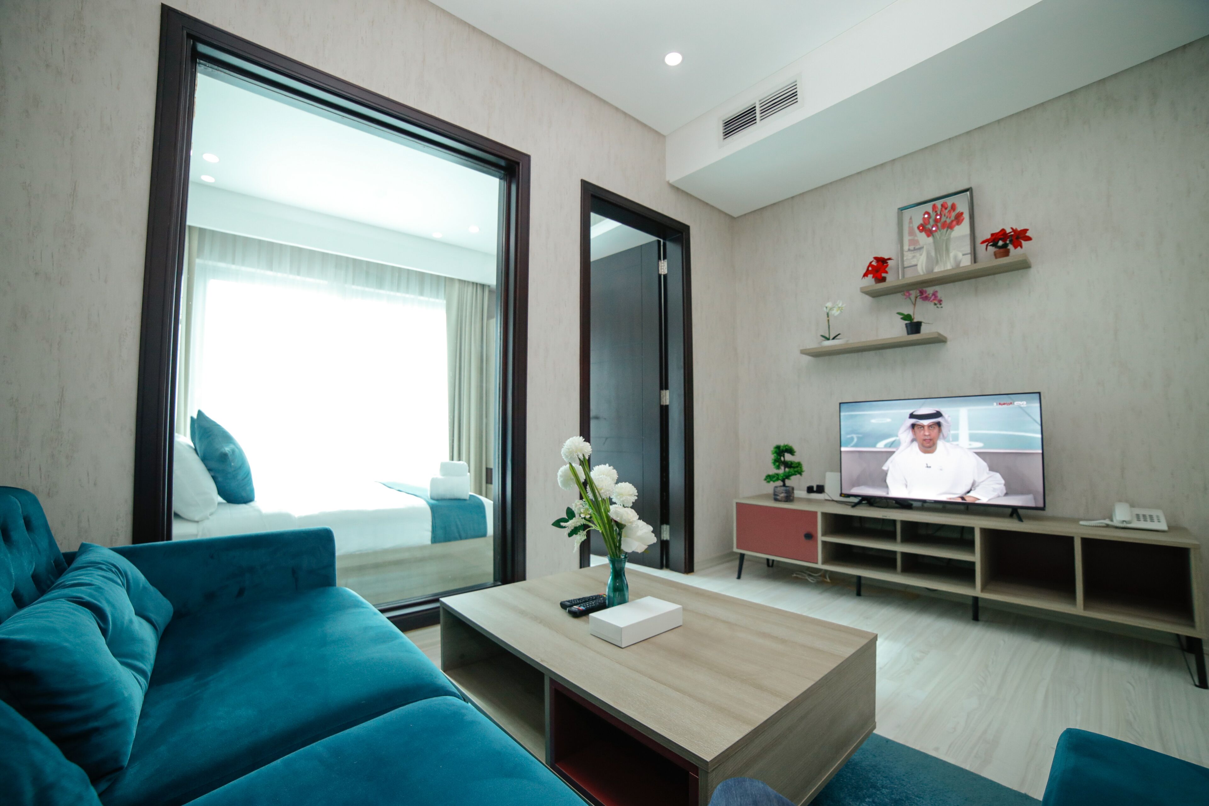 Uma sala de estar moderna com sofá, mesa de centro com vaso, televisão e cama com cortinas.