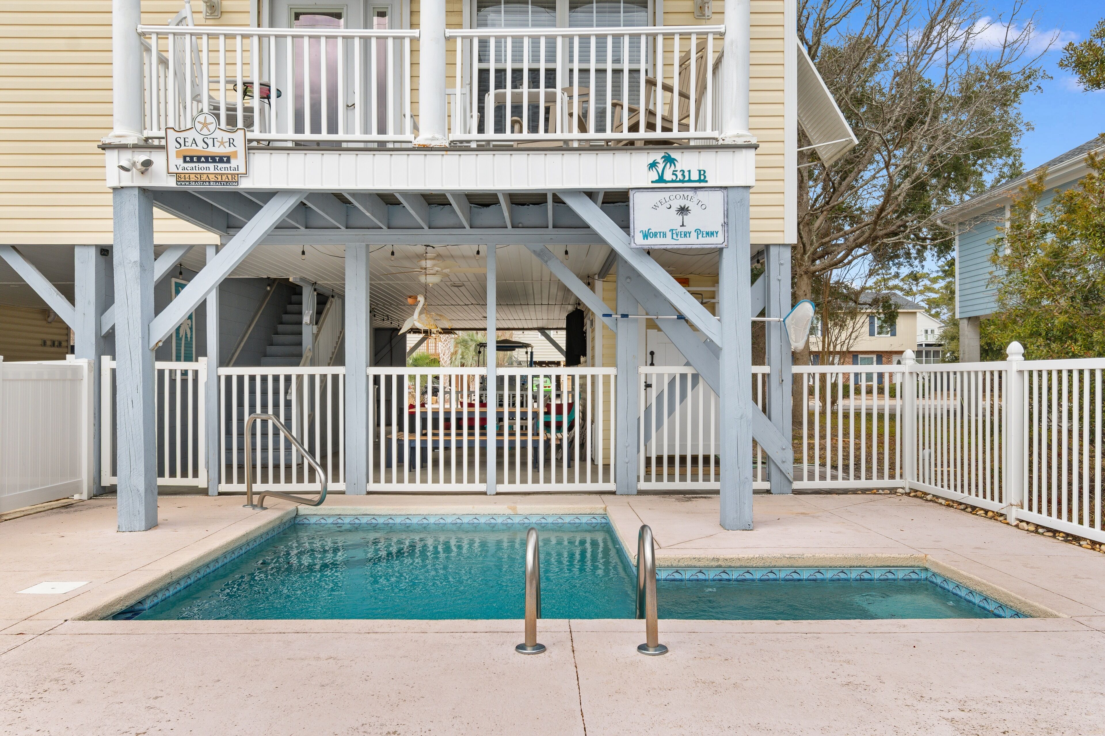 A pool area with a sign for Seastar Vacation Rental and a welcome sign for Worth Every Penny.