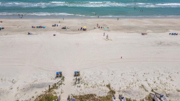 Ein Strand mit Menschen, Sonnenschirmen und Liegestühlen.