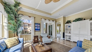 A spacious living room with a large window, a sofa set, a coffee table, and a white cabinet. - Stunning 3 Bedroom / 2.5 Bath Condo Steps from Siesta Key Beach! (Siesta Key)
