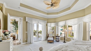 A spacious bedroom with a large bed, a ceiling fan, and a view of the outside balcony. - Stunning 3 Bedroom / 2.5 Bath Condo Steps from Siesta Key Beach! (Siesta Key)