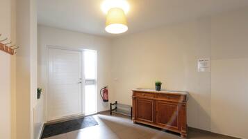 A hallway with a white door, a radiator, a wooden cabinet, and a fire extinguisher.