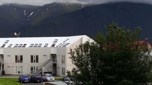 A building with a flat roof, multiple windows, and a staircase leading to the entrance. - The Private Apartments (Borgarnes)