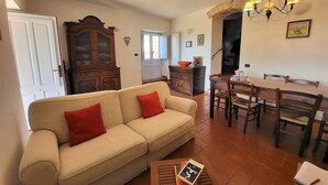 Una sala de estar con un sofá color crema, una mesa de comedor de madera con sillas, una araña y un aparador.