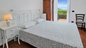 Un dormitorio con cama, mesita de noche, lámpara, armario de madera y una silla.