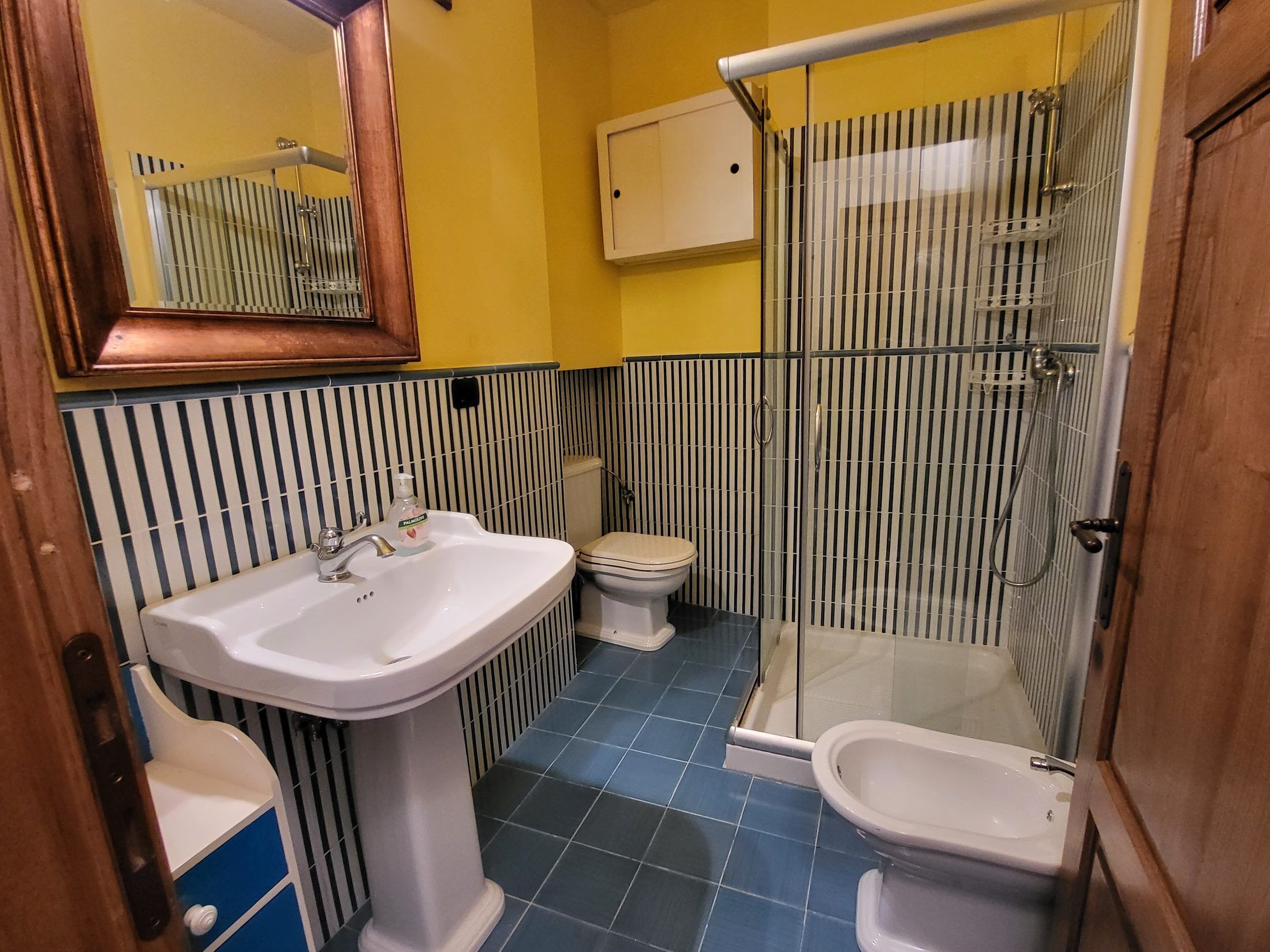 Une salle de bain comprenant un lavabo sur colonne, des toilettes, un bidet et une douche à parois de verre.