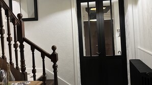A staircase with wooden balusters, a black door with glass panels, and a hexagonal patterned floor. - La maison de Louisette (Le Faouet)