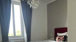 A bedroom with a bed, a desk, and a chandelier. - La maison de Louisette (Le Faouet)