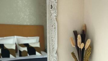 Quarto com um espelho grande e ornamentado, um certificado emoldurado e dois vasos decorativos.
