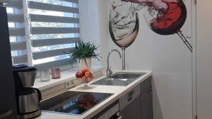 Eine moderne Küche mit eingebautem Geschirrspüler, einer Spüle mit zwei Becken und einem großen Fenster mit Jalousien.