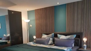 Ein modernes Schlafzimmer mit einem großen Bett, einem Nachttisch mit Lampe und einem Spiegel.
