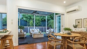 An open-plan living area with a dining table and chairs, a sofa, and a ceiling fan.