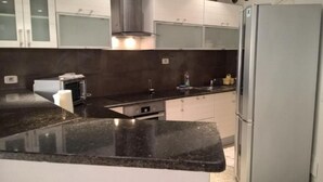 Een moderne keuken met een zwart granieten aanrecht, roestvrijstalen apparatuur en witte kastjes.
