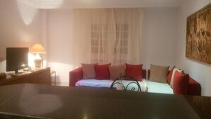 Een woonkamer met een bank, een televisie en een lamp.