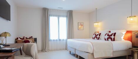 A modern hotel room with a large bed, a desk, and a chair.