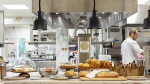 A bakery display with various baked goods and a chef in the background.