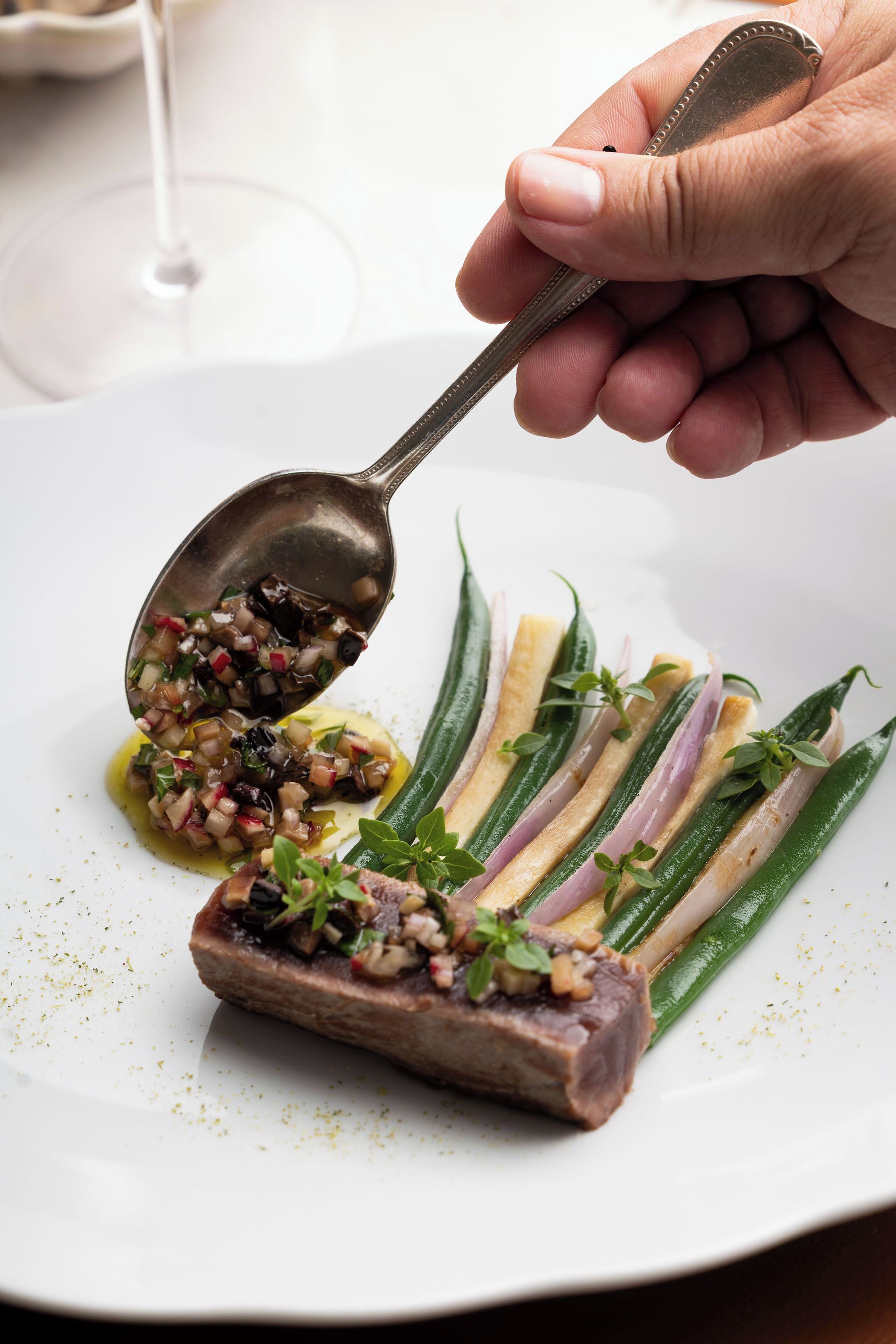 Una porción de comida servida en un plato con un filete y verduras verdes.