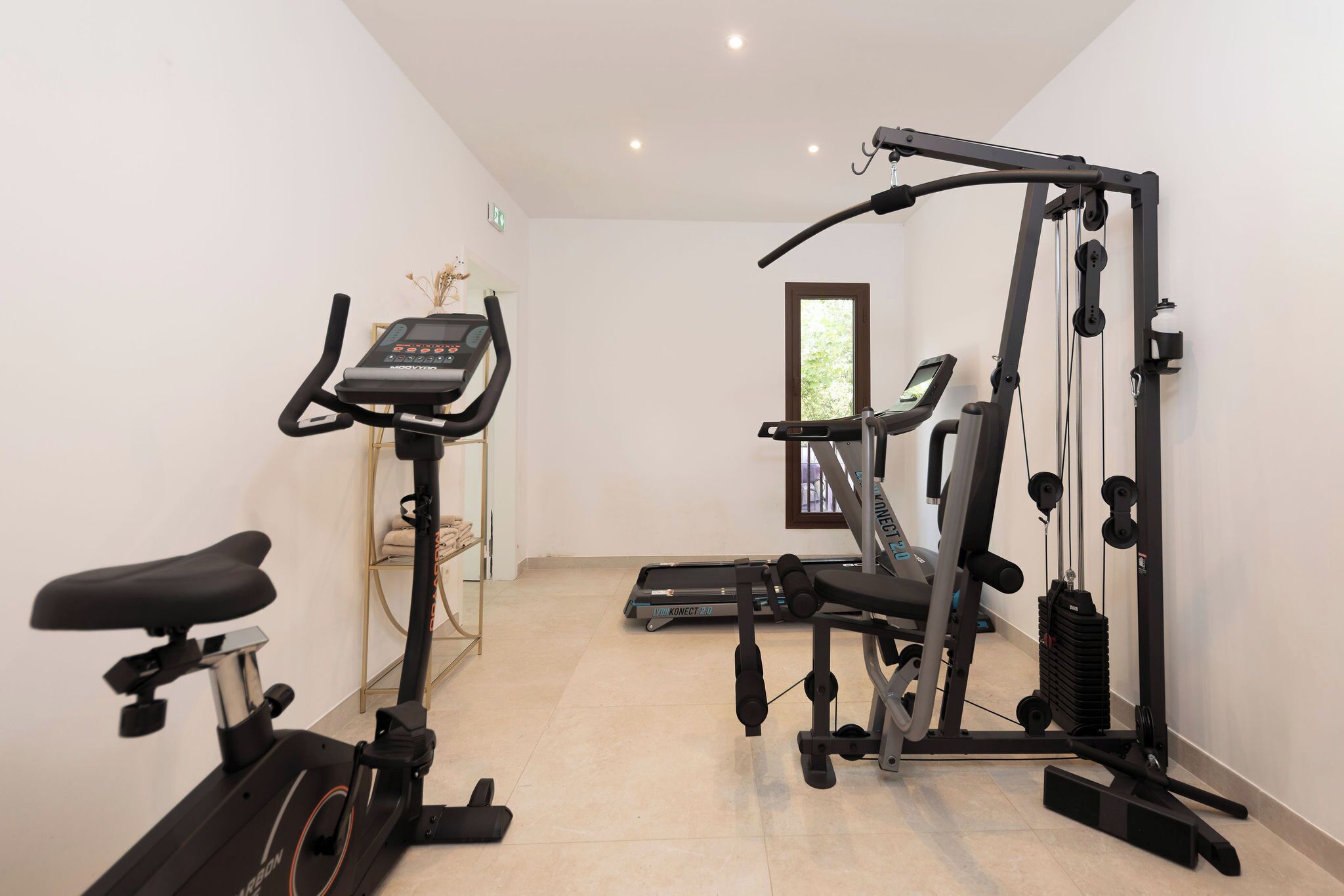Gimnasio en casa con bicicleta estática, elíptica y máquina de pesas.