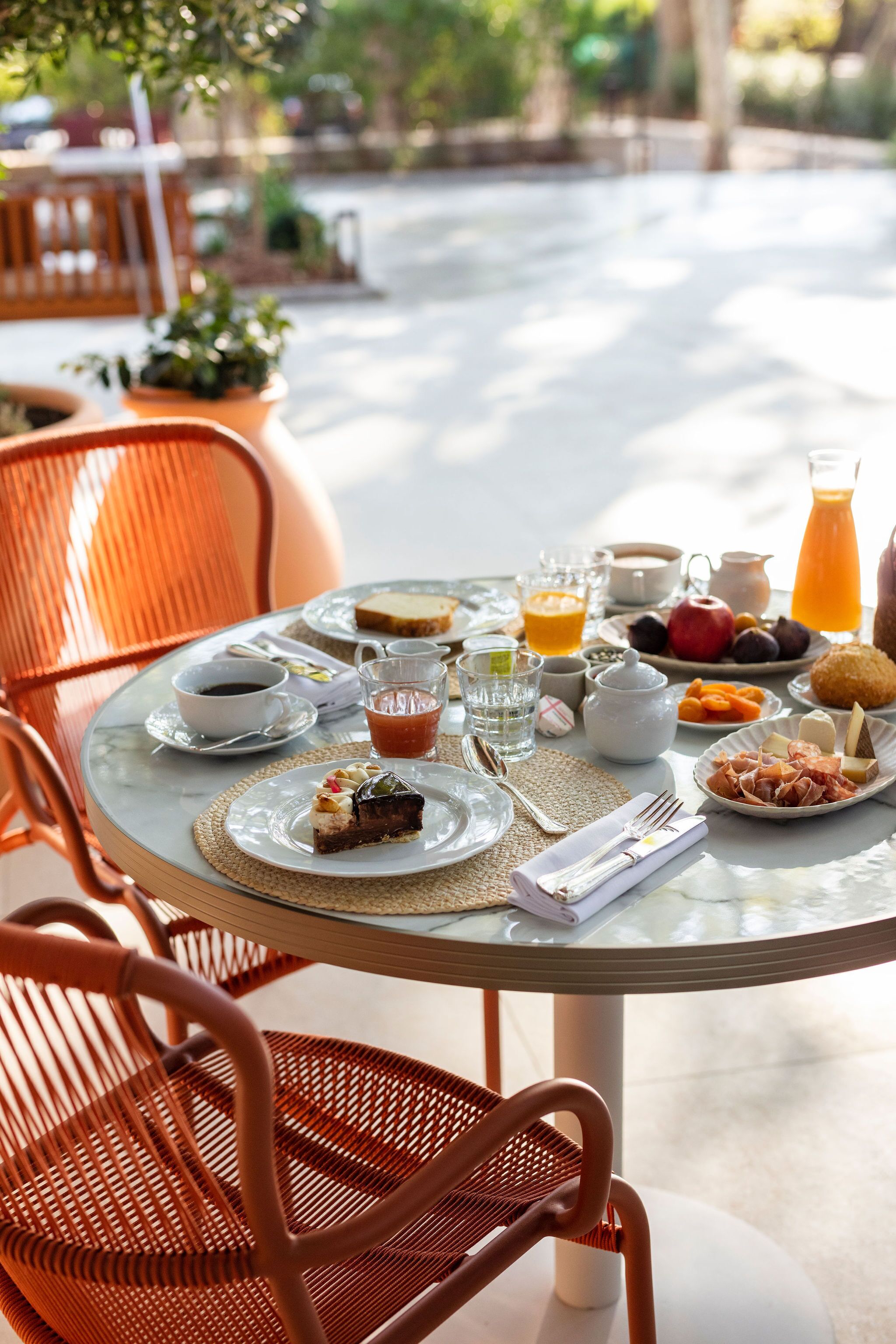 A round glass table set with breakfast items, including plates of food, cups, and a teapot.