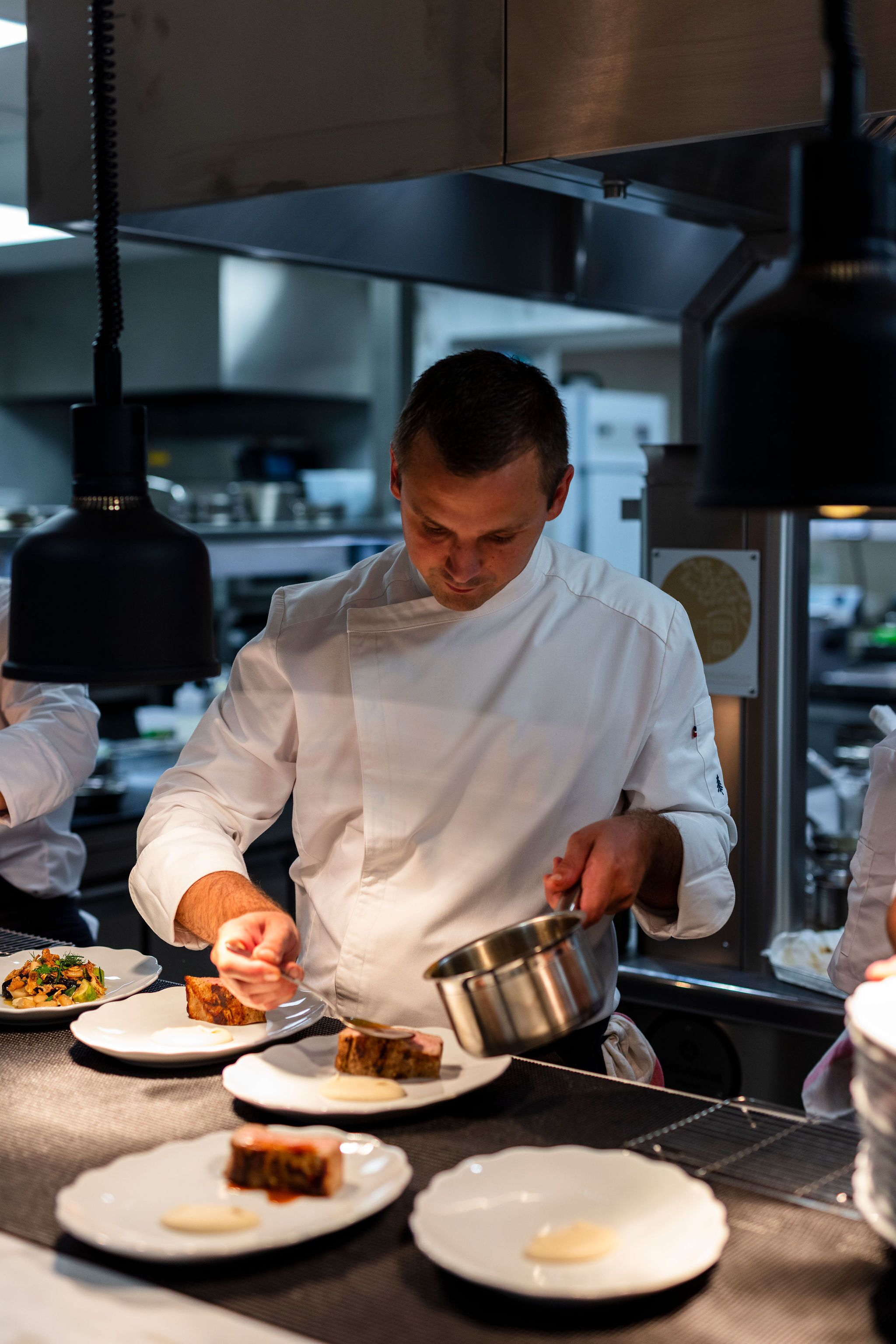 Un chef preparando comida en una cocina profesional con superficies de acero inoxidable y equipamiento moderno.