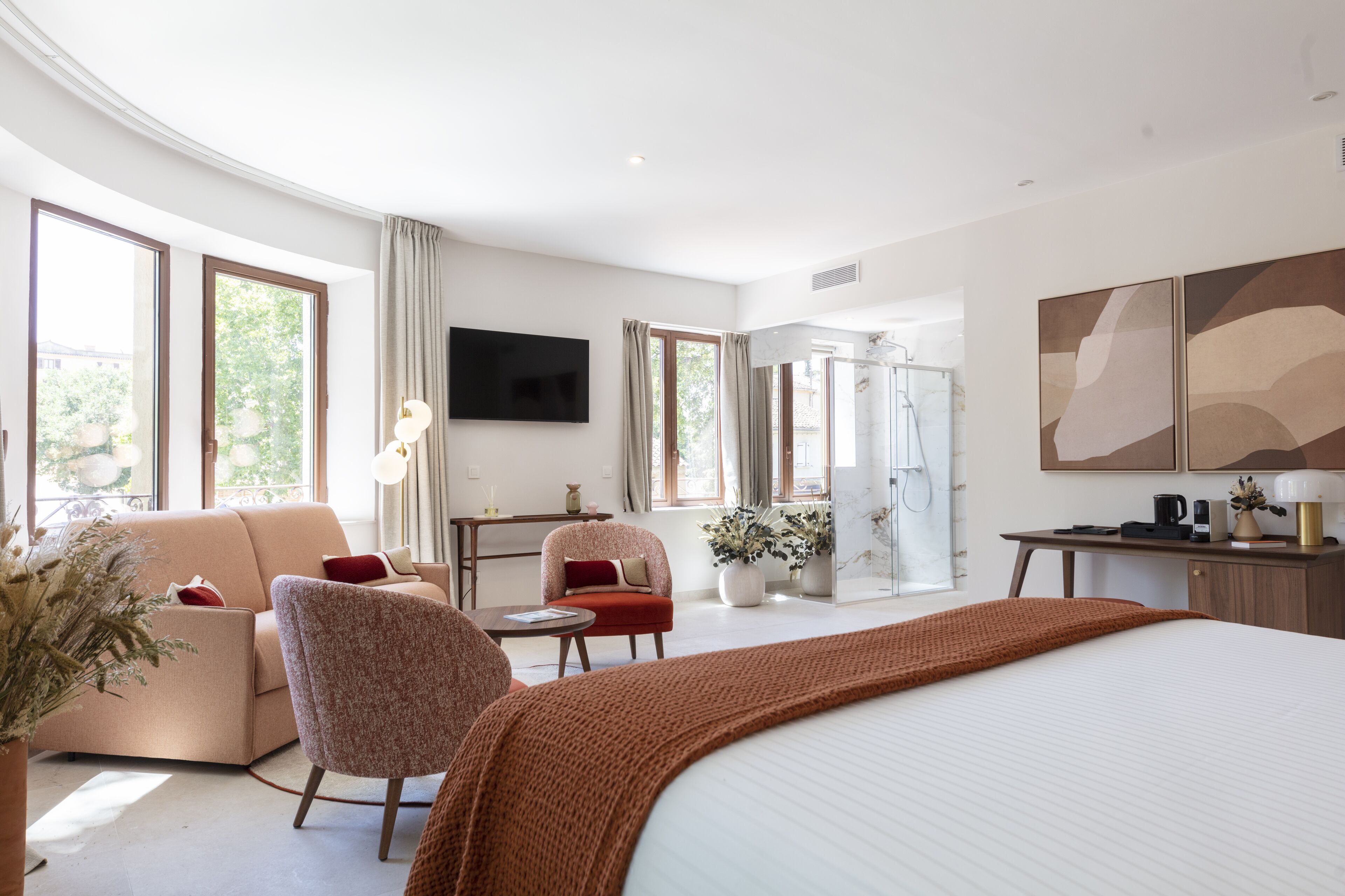 Una habitación de hotel moderna con una cama grande, un sofá, una silla, un escritorio y un televisor.