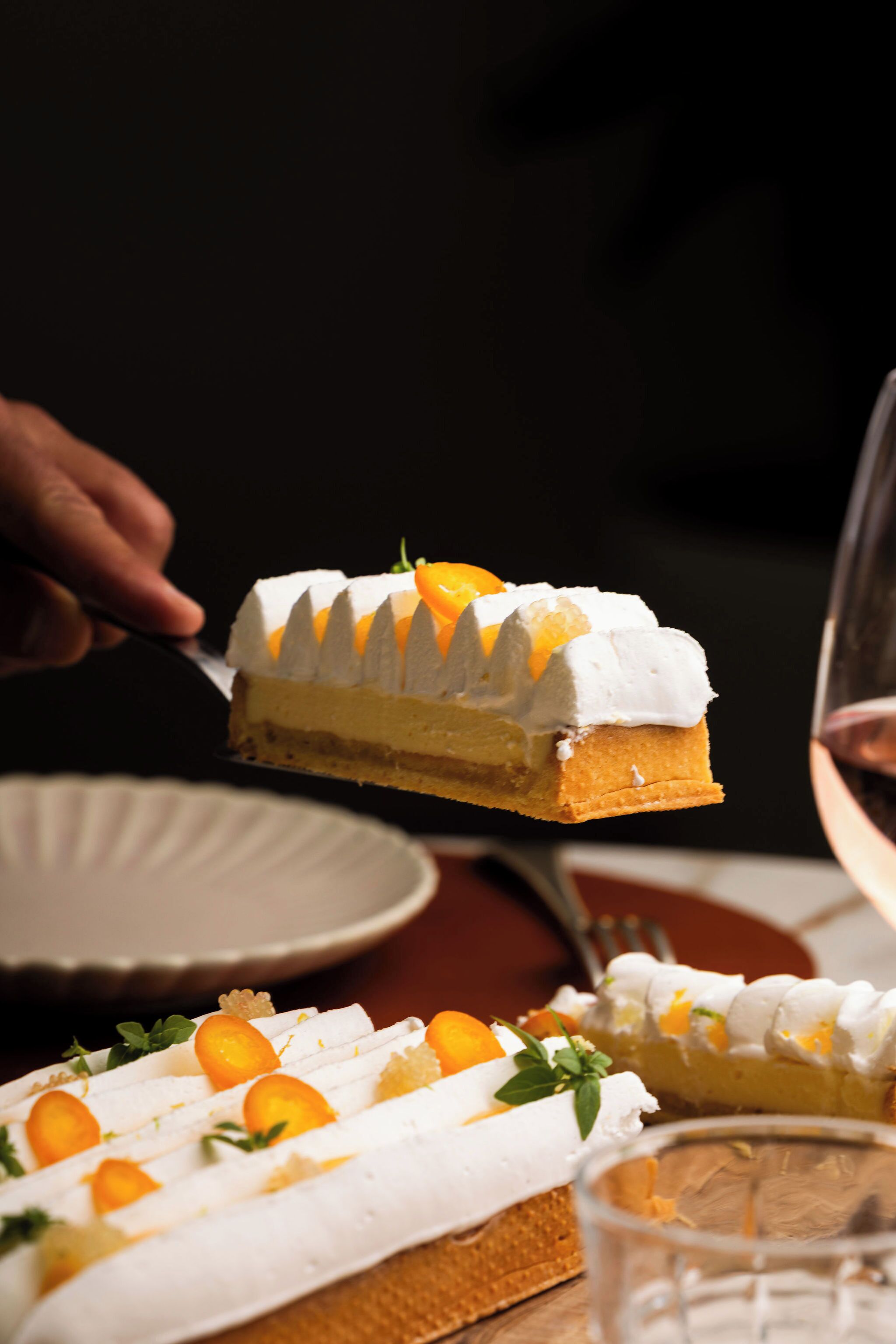 A slice of cake with white frosting and orange slices on a plate.