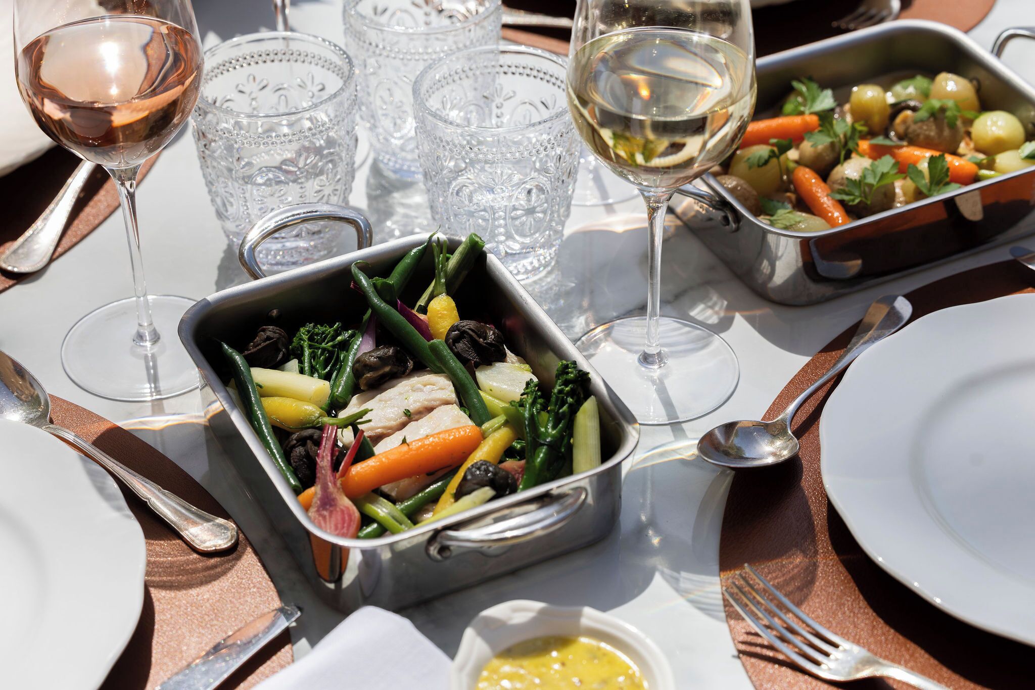 Una mesa de comedor con comida, vasos y cubiertos.