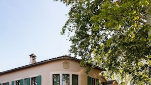 A pool area with lounge chairs and umbrellas, a building with a sign reading "LA BASTIDE BOURRELY," and a reflection in the pool.