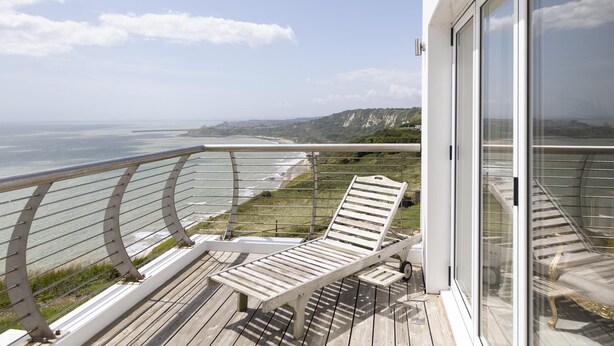 Ein Balkon mit Blick auf das Meer und eine Rasenfläche.