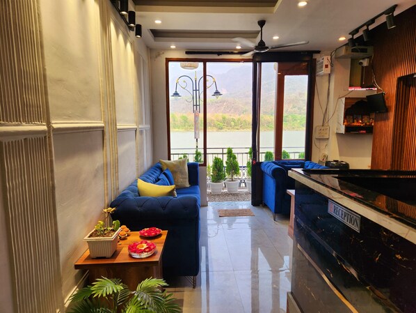 A modern reception area with a blue sofa, a reception desk, and a view of a lake through large windows.